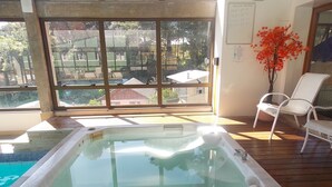 Un bain à remous sur une terrasse en bois, avec vue sur un quartier résidentiel grâce à de grandes fenêtres.
