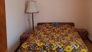 Une chambre à coucher avec un lit recouvert d’une couvre-lit à motifs floraux, une lampe sur pied et un lustre.