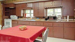 Une cuisine avec des meubles de couleur marron, une nappe rouge et un four à micro-ondes.