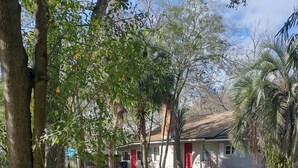 Un quartier résidentiel avec une maison dotée d’une porte rouge, entourée d’arbres et bordée d’une allée en gravier.