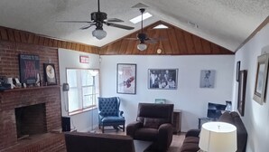 Un salon spacieux doté d’une cheminée, de sièges confortables et d’un ventilateur de plafond.