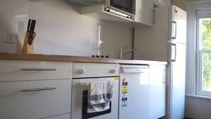 Una cocina con armarios blancos, un microondas, un horno y un refrigerador.