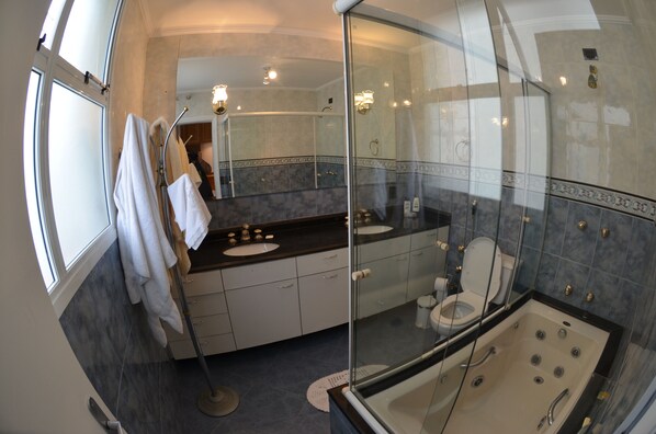 Un baño moderno con ducha de vidrio, bañera y tocador con lavamanos y espejo.