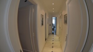 A hallway with white walls, a tiled floor, and doors on both sides.