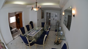 A dining area with a glass table, blue upholstered chairs, and a chandelier.
