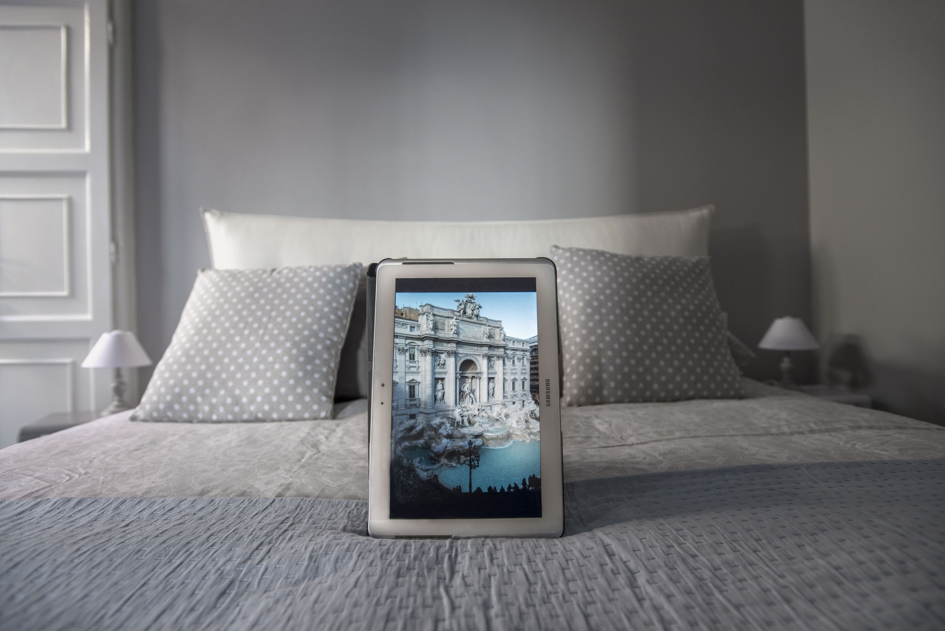 Un teléfono inteligente sobre una cama mostrando un edificio con una fuente grande.