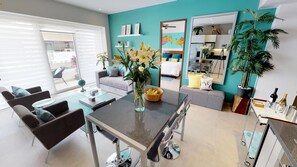 A modern living room with a sofa, a dining table, and a kitchen area visible through an open door. - El Paraiso Pavilion 2BD Condo for rent in Old Town, Puerto vallarta (Puerto Vallarta)
