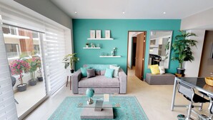 Una sala de estar moderna con una pared de acento color turquesa, un sofá gris y una mesa de centro de vidrio con piezas de ajedrez.