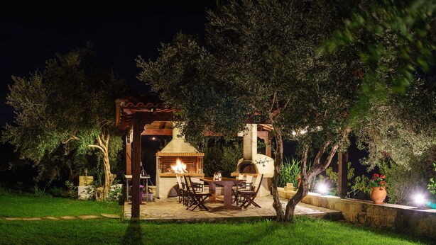 An outdoor patio area with a fire pit, seating, and a stone wall.