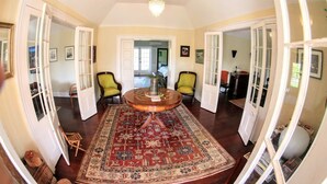 Une pièce spacieuse avec une table ronde en bois, deux chaises, un tapis rouge à motifs et un lustre.