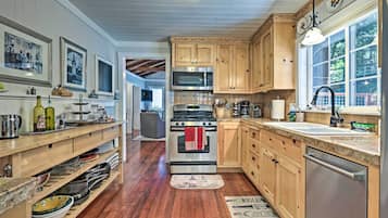 Une cuisine avec des armoires en bois, des appareils en acier inoxydable et un plancher en bois.