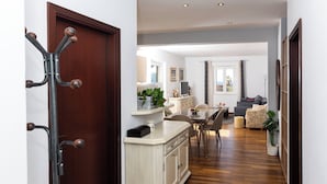 Ein Flur, der in einen Essbereich mit Holzboden, einem weißen Schrank und einem Garderobenhaken führt.