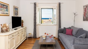 Ein Wohnzimmer mit Couch in Grau, Holz-Couchtisch und Fernseher auf einem Schrank.