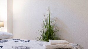 A neatly made bed with a patterned bedspread, a bedside plant, and a wall with four framed pictures. - Charming Duplex in the Heart of the Old Town (Split)