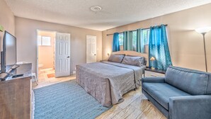 A bedroom with a bed, a desk, a chair, a sofa, and a TV.