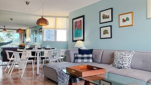 A modern living room with a sofa, coffee table, and dining area with chairs.