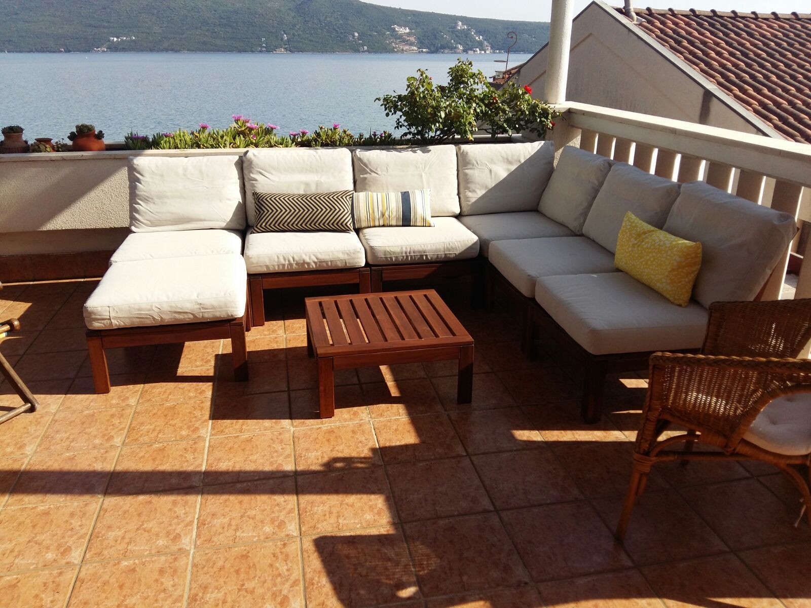 Une terrasse avec un ensemble de canapés, une table en bois et une chaise en osier.