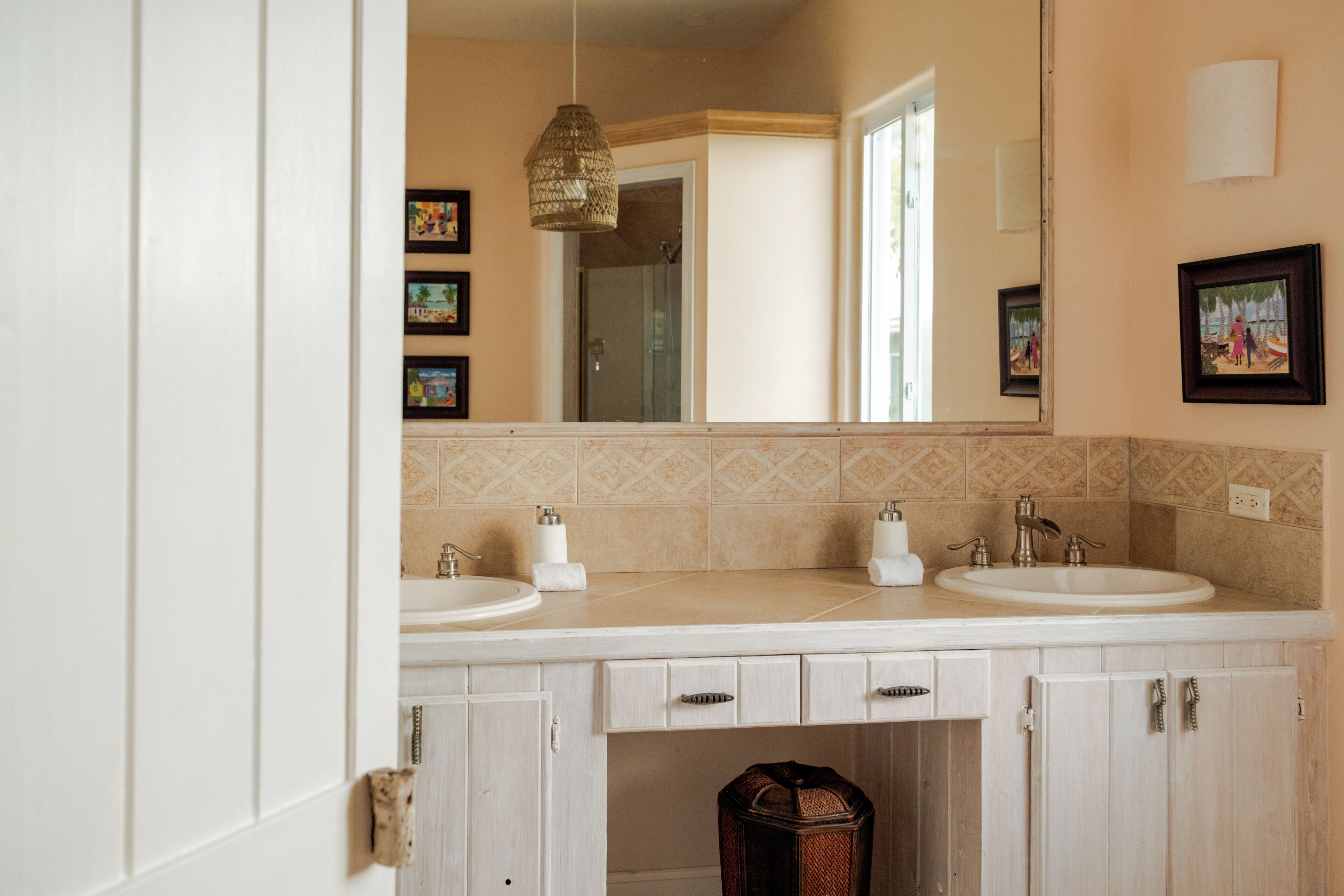 Une salle de bain avec deux lavabos, un miroir et un luminaire suspendu.