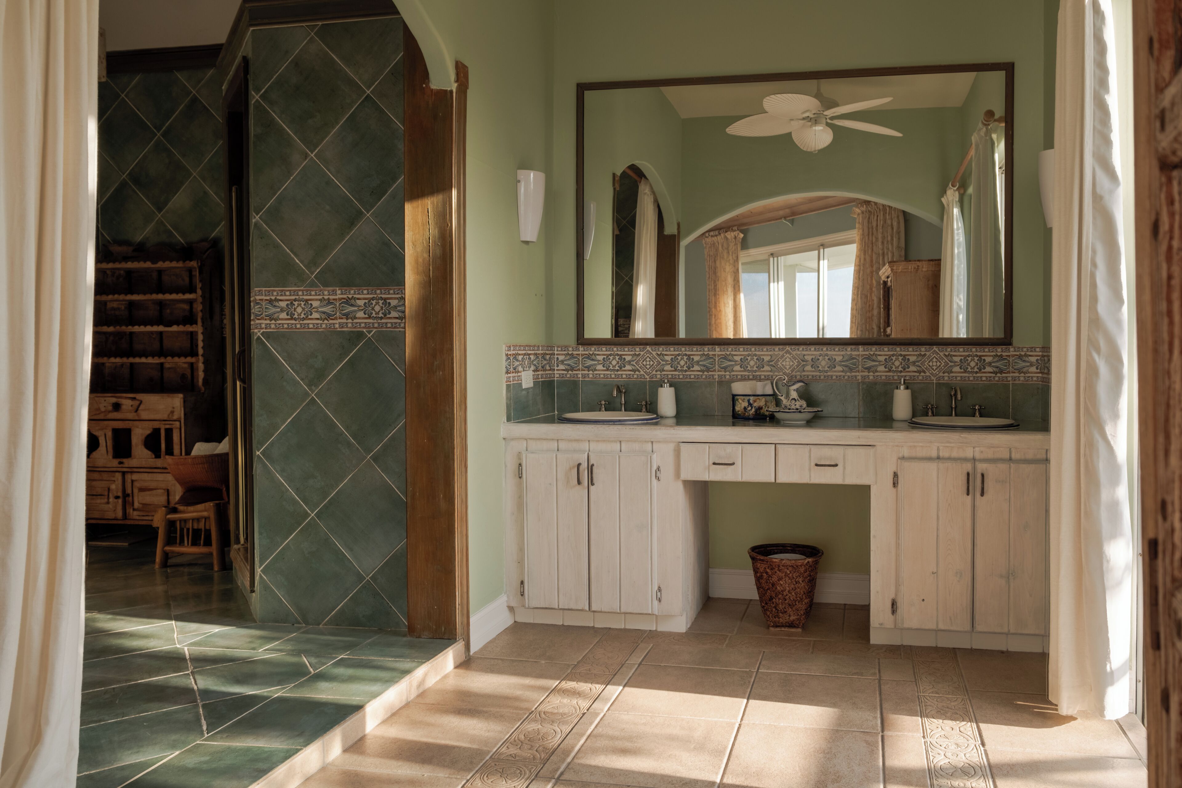 A bathroom with a large mirror, a ceiling fan, and a tiled floor.