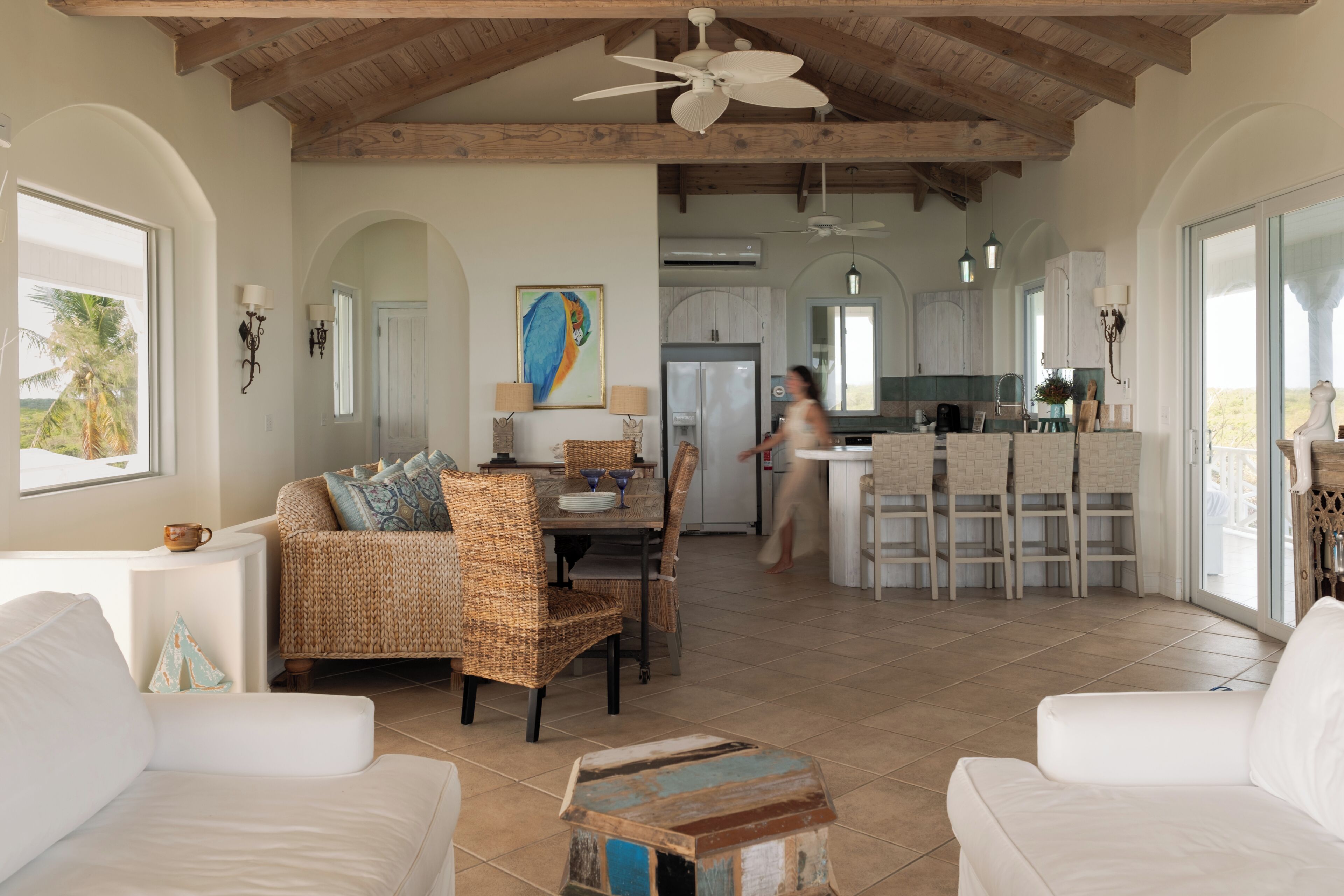 A spacious living area with a dining table, wicker chairs, and a white sofa.