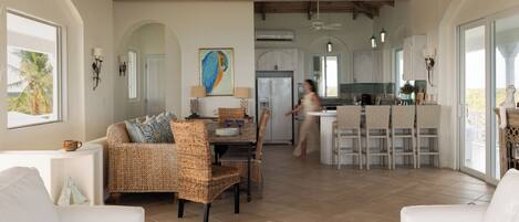 A spacious living area with a dining table, wicker chairs, and a white sofa.