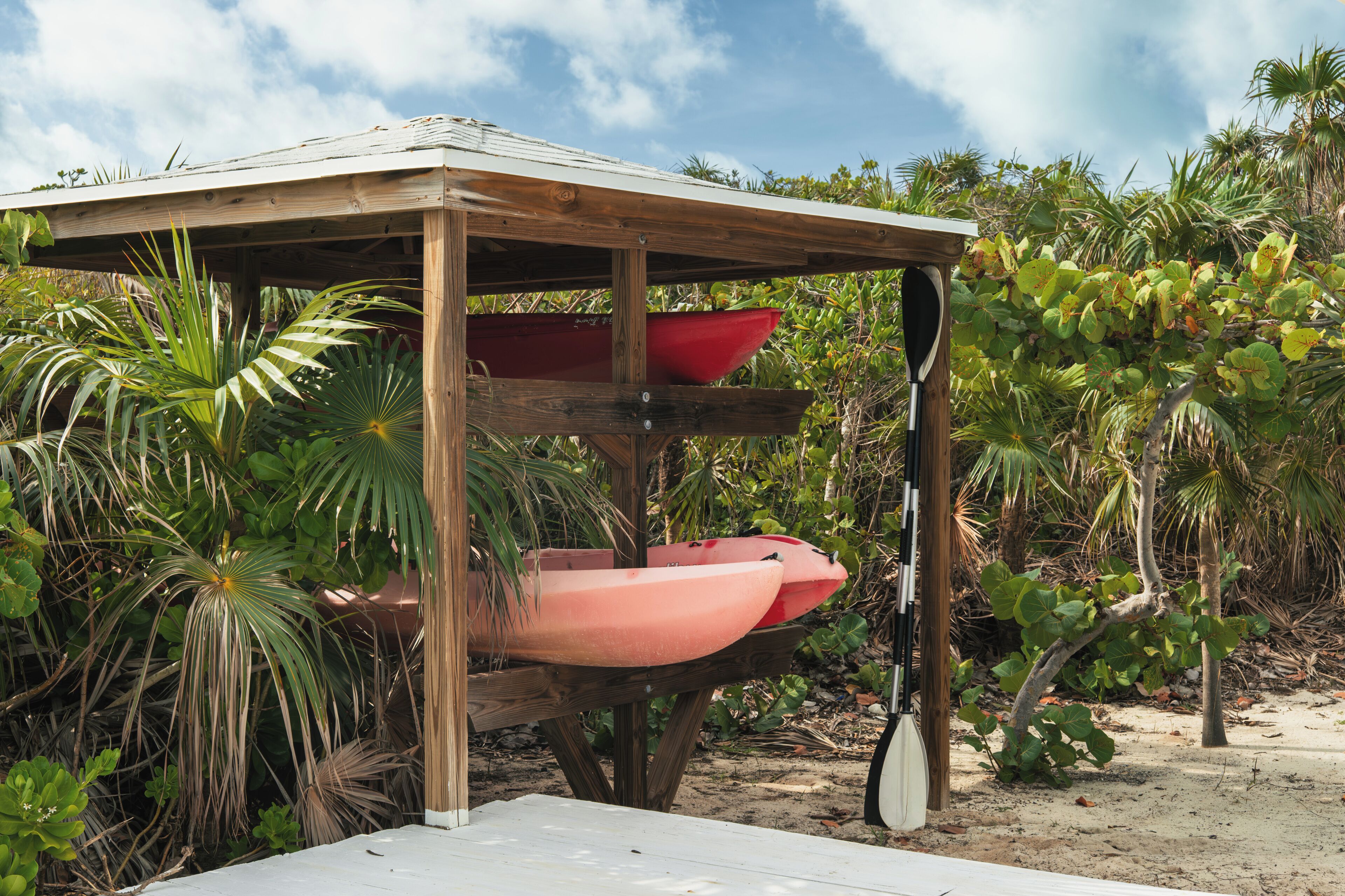 A wooden structure with kayaks and a paddle leaning against it.
