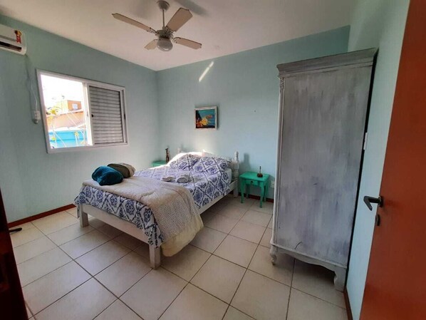 A bedroom with two beds, a wardrobe, a ceiling fan, a window, and a small table.