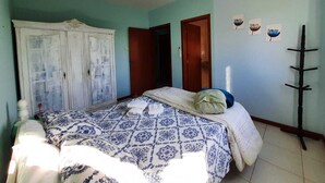 Een slaapkamer met een bed, een kledingkast, een plafondventilator en een wandkapstok.