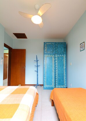 Ein Zimmer mit zwei Betten, einem Deckenventilator und einem blauen Kleiderschrank.