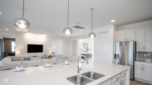 A modern kitchen with a large island, stainless steel appliances, and pendant lighting. - Sonoma Resort affordable 7bd home with pool (1849) (Kissimmee)