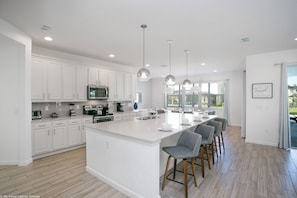 Una cocina moderna con gabinetes blancos, una isla grande y taburetes de bar.