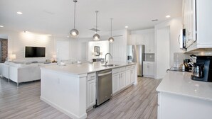A modern kitchen with white cabinetry, stainless steel appliances, and pendant lighting. - Sonoma Resort affordable 7bd home with pool (1849) (Kissimmee)