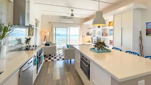 Una cocina moderna con una isla grande, electrodomésticos integrados y vistas al exterior.