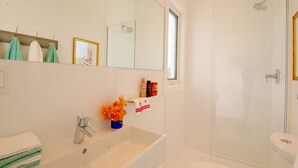 Un baño con lavabo, espejo, ducha e inodoro.