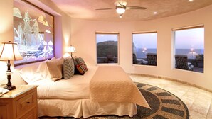 A bedroom with a bed, nightstands, a ceiling fan, and large windows with a view of the sea. - Luxury Oceanfront Villa in Cabo San Lucas (Cabo San Lucas)