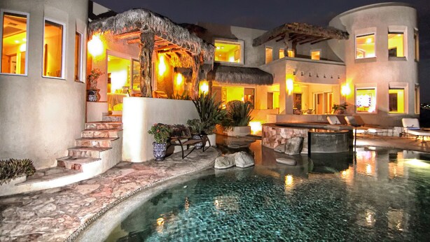 A resort with a swimming pool, outdoor seating, and a thatched-roof structure. - Luxury Oceanfront Villa in Cabo San Lucas (Cabo San Lucas)