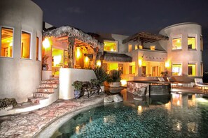 Un resort con piscina, mobiliario exterior y una estructura de techo de paja.