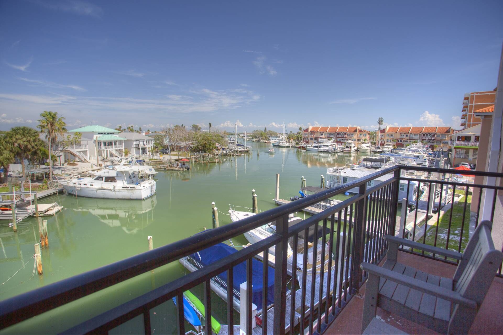A marina with boats docked, a building with a green roof, and a clear sky.