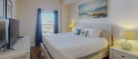 A bedroom with a bed, bedside tables, a TV, and a painting on the wall.