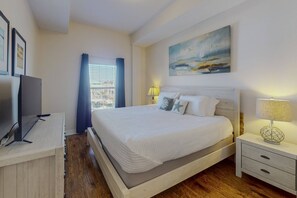 A bedroom with a bed, bedside tables, a TV, and a painting on the wall. - Across from Beach, Heated Pool, with Marina View from Private Balcony. Great Location! (Madeira Beach)