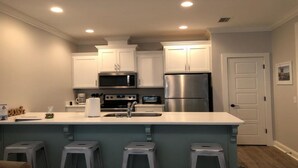 A modern kitchen with white cabinets, stainless steel appliances, and a bar area with stools.