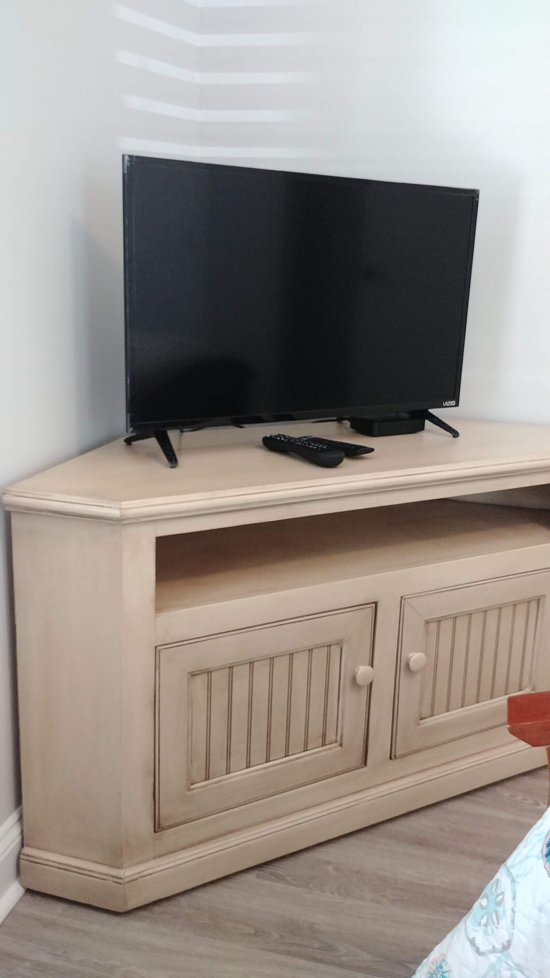 A television on a beige cabinet with two doors and a remote control.