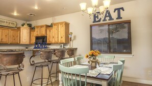 Una cocina con armarios de madera, una araña y una mesa de comedor con sillas.