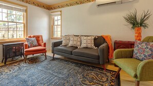 Una sala de estar con sofá, sillones, una mesita y una planta decorativa.