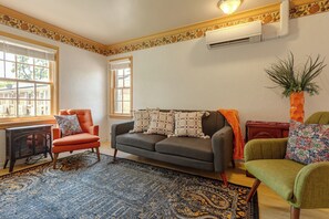 A living room with a sofa, armchairs, a small table, and a decorative plant.