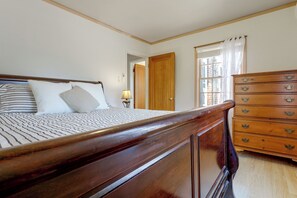 Un dormitorio con una cama de madera, un aparador y una puerta que da a otra habitación.
