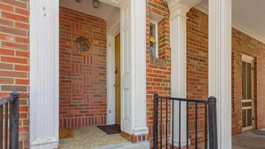 Un edificio de ladrillo con porche, columnas y una puerta.