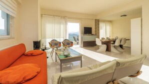 Un vaste espace de vie comprenant un canapé, des fauteuils, une table basse et un téléviseur.