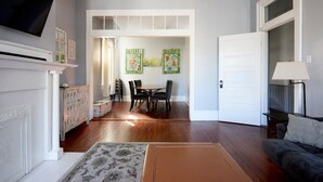 A living room with a fireplace, a dining area with a table and chairs, and a door leading to another room. - Downtown Savannah Oasis 6 beds 3 baths (Savannah)