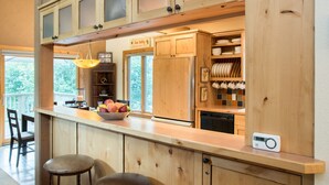 Een keuken met houten kastjes, een fruitschaal en een koffieapparaat.
